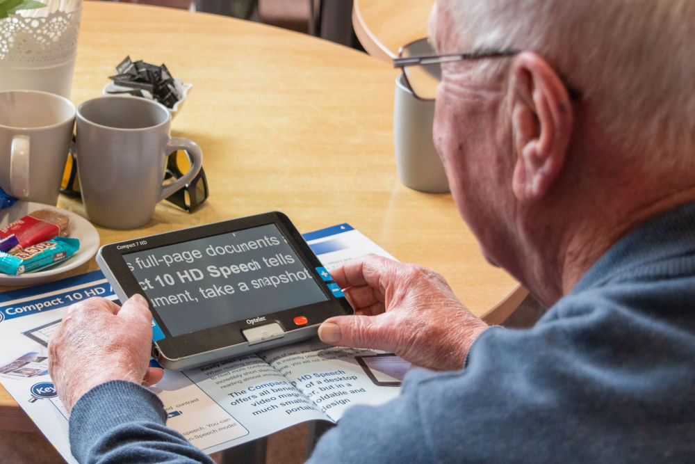 Member of social group using a digital magnifier to read a magazine 